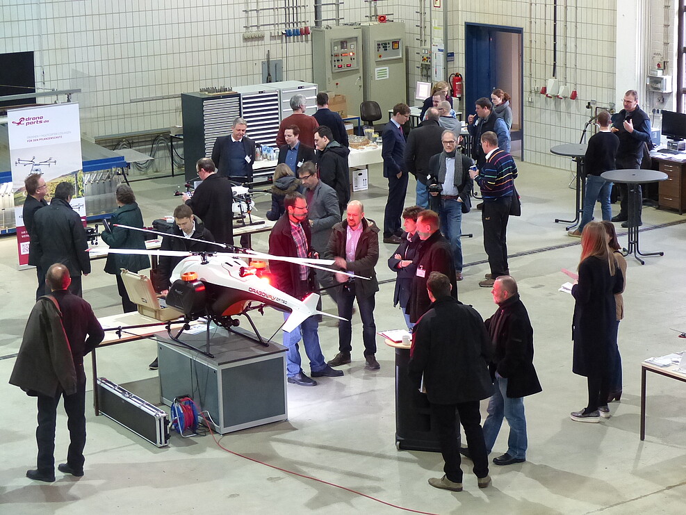 unmanned aerial vehicles in an exhibition hall, surrounded by workshop participants