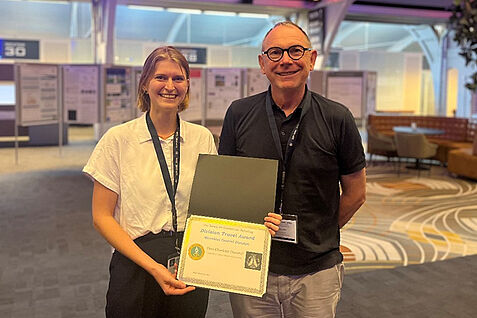 Lina Dammel mit ihrem Betreuer Prof. Dr. Johannes Jehle und der Urkunde des SIP Travel Awards (© Jörg Wennmann/JKI).