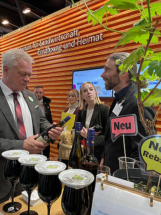 Prof. Dr. Oliver Trapp überreicht Bundeslandwirtschaftsminister Alois Rainer eine Flasche mit JKI-Piwi-Wein als Gastgeschenk auf dem Biofach-Stand. © J. Fuchs/JKI