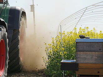 Sprayer drives through rape field with beehive on it