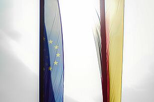 Transluscent flags of Germany and the EU against the bright sky..